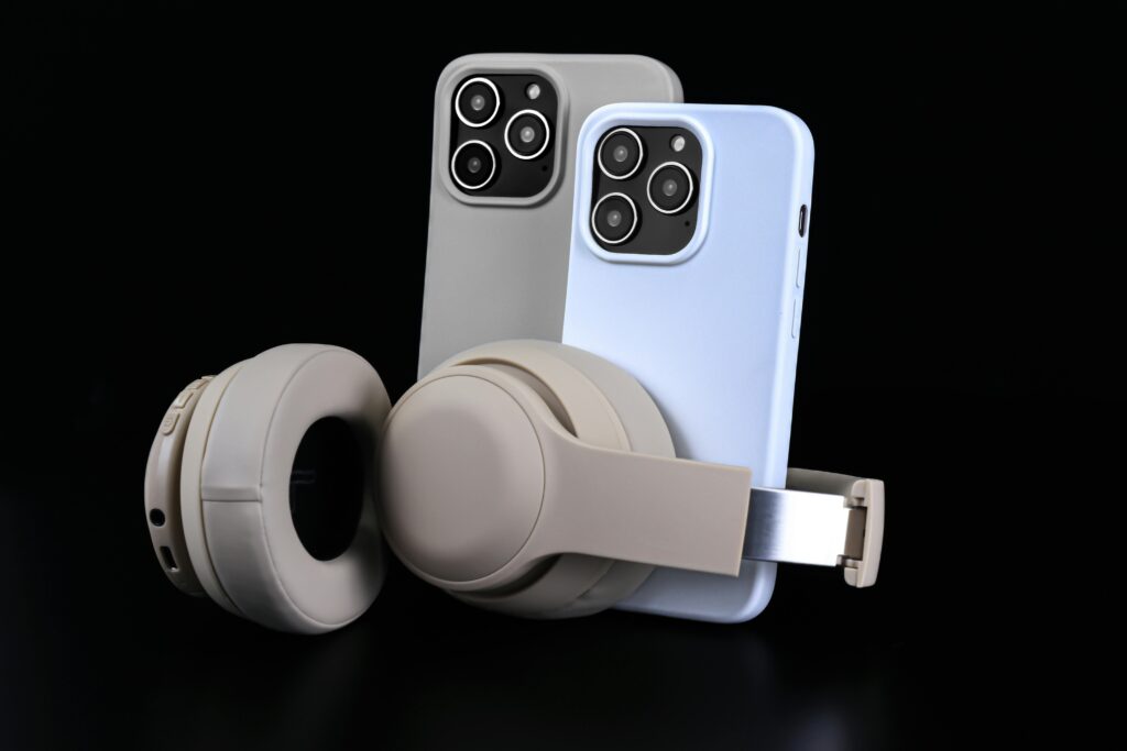 Pair of smartphones with beige headphones on black background, showcasing modern technology.