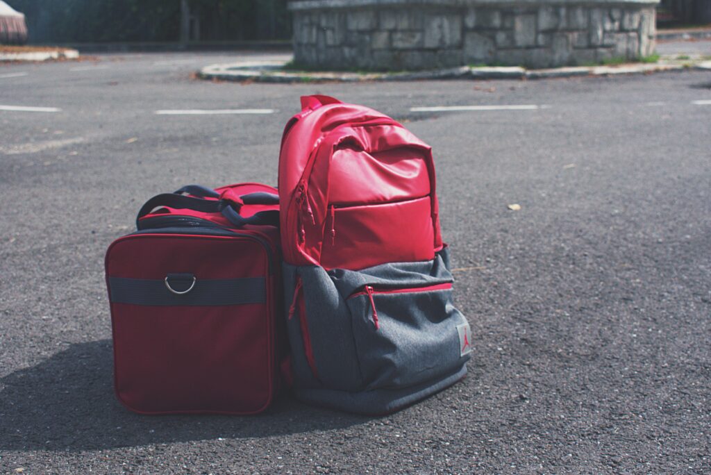 Red backpack and matching bag on asphalt, perfect for travel themes.